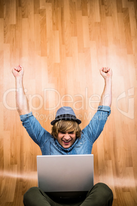 Cheerful blond hipster looking at laptop