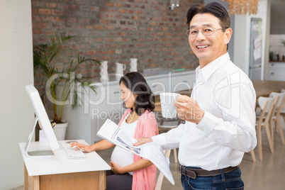 Smiling man reading newspaper and having coffee