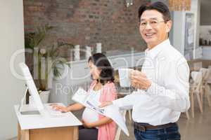 Smiling man reading newspaper and having coffee