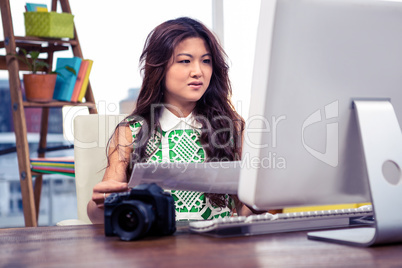 Creative businesswoman holding document and looking at computer
