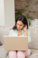 Unsmiling brunette using laptop