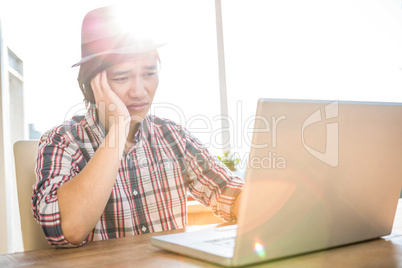 Worried hipster businessman using laptop