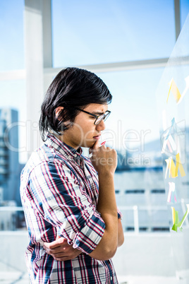 Thoughtful creative businessman looking at sticky notes