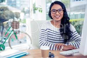 Smiling Asian woman sitting at desk posing for camera