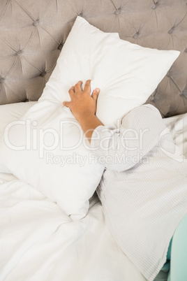 Pregnant woman covering face with pillow