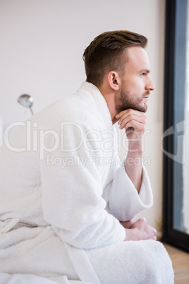 Serious man in bathrobe looking away