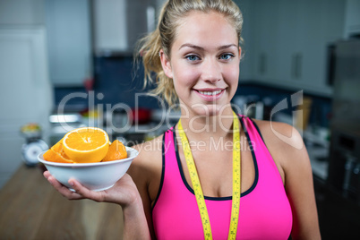 Fit woman showing a bowl of oranges