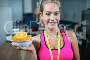 Fit woman showing a bowl of oranges