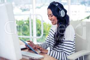 Smiling Asian woman with headphones using tablet