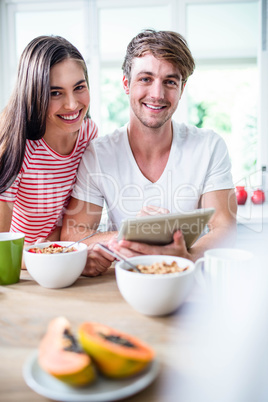 Happy couple using tablet and having breakfast