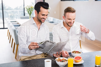 Smiling gay couple reading newspaper