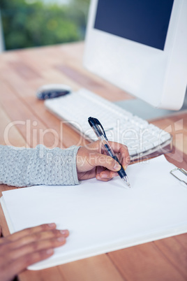 Womans hand writing with pen on white sheet