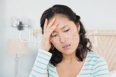 Woman with head ache sitting on bed