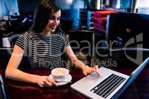 Woman having coffee and using laptop