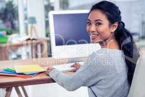 Smiling Asian woman using computer looking back at the camera