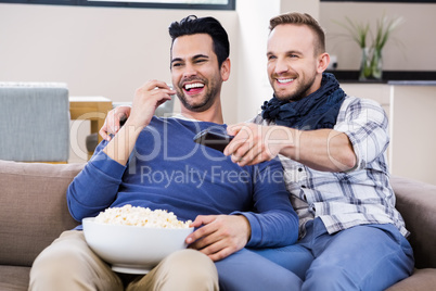 Gay couple watching television with pop corn