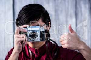Hipster taking pictures with an old camera while making thumbs u