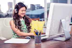 Smiling Asian woman with headphones using computer