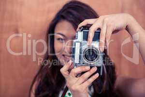 Smiling Asian woman taking photograph with camera