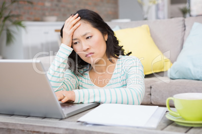 Frowning brunette using laptop