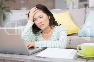 Frowning brunette using laptop