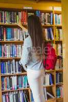 Smiling brunette student picking out book