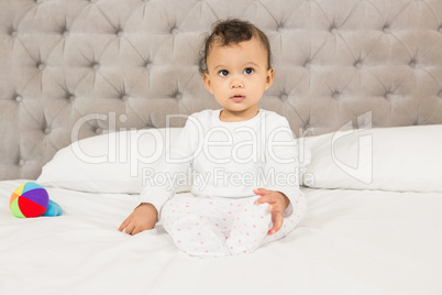 Cute baby sitting on bed