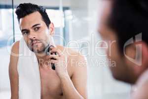 Handsome man shaving in the mirror