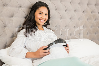 Pregnant brunette putting headphones on belly