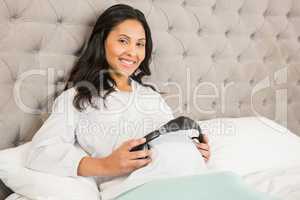 Pregnant brunette putting headphones on belly