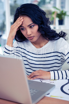 Pretty woman looking at computer monitor with hand on head