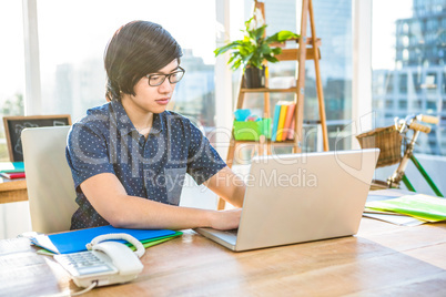 Smiling hipster businessman using laptop