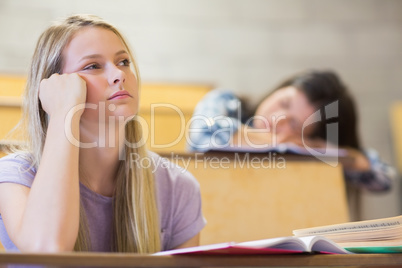 Bored student listening while classmate sleeping