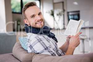Handsome man reading a book on the couch