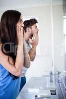 Young couple looking themselves in the mirror