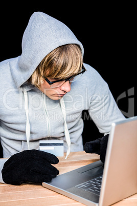 Man in hood jacket hacking a laptop