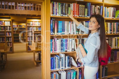 Smiling brunette student picking out book