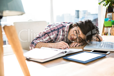 Hipster businessman falling asleep on desk