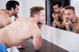 Unsmiling men in front of mirror
