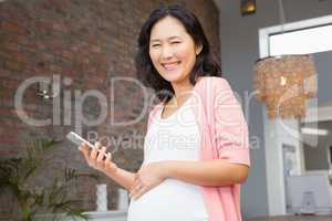 Smiling pregnant woman holding smartphone