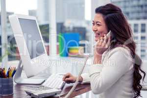 Smiling Asian woman on phone call using computer