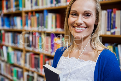 Smiling female student listening to music in the library
