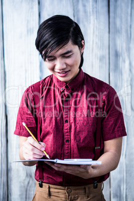 Smiling hipster takes notes with his smartphone