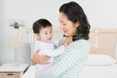 Smiling mother carrying baby daughter