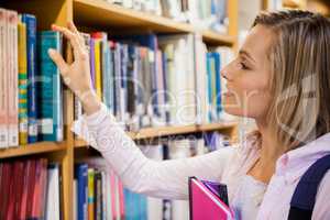Female student picking a book in the library
