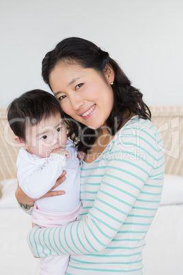 Smiling mother carrying baby daughter