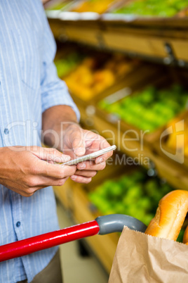 Man texting and grocery shopping