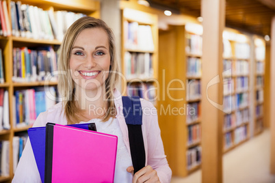 Female student holding textbooks in the library