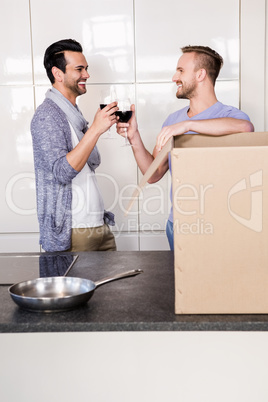 Smiling gay couple drinking red wine