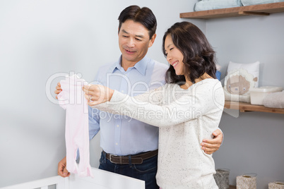 Happy couple holding white onesie